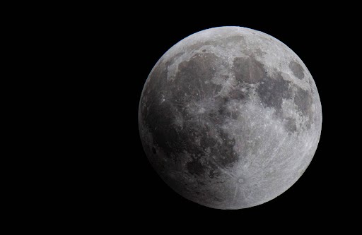A silver moon emerging from deep darkness